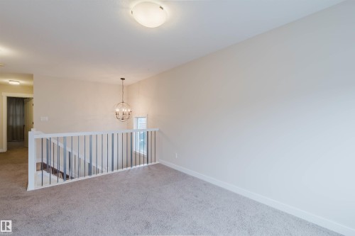 Loft area featuring neutral carpeting, light-colored walls, and a modern globe-style chandelier - 2878 Koshal Crescent, Edmonton, AB - Indoor Photo Showing Other Room