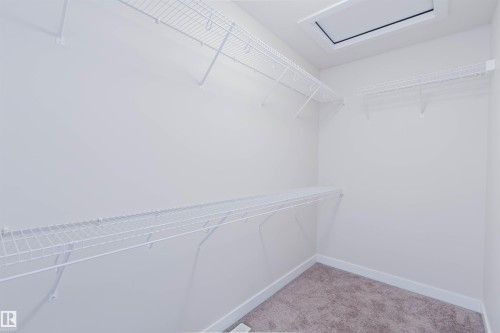 Spacious closet featuring white wire shelving, light-colored carpeting, and a ceiling access panel - 2878 Koshal Crescent, Edmonton, AB - Indoor With Storage