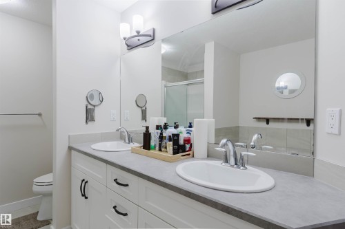 Bathroom featuring a double vanity with white cabinetry, a large mirror, and modern lighting fixtures - 2878 Koshal Crescent, Edmonton, AB - Indoor Photo Showing Bathroom