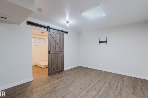 Room featuring wood-look flooring, a modern barn door, and recessed lighting - 2878 Koshal Crescent, Edmonton, AB - Indoor Photo Showing Other Room