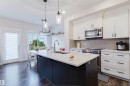The kitchen features a central island with a sink, white countertops, and dark cabinetry - 2878 Koshal Crescent, Edmonton, AB  - Indoor Photo Showing Kitchen With Double Sink With Upgraded Kitchen 
