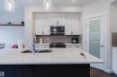 The kitchen features white cabinetry, a stainless steel microwave, and a grey subway tile backsplash - 2878 Koshal Crescent, Edmonton, AB  - Indoor Photo Showing Kitchen With Double Sink 