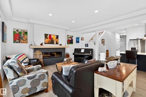 Spacious living area featuring a modern fireplace with a light wood mantel, hardwood flooring, and recessed lighting - 345 Meadowview Drive, Fort Saskatchewan, AB - Indoor Photo Showing Living Room With Fireplace