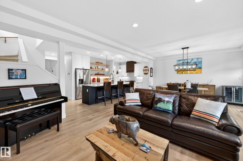 Open-concept main living area with light wood flooring, a kitchen featuring an island with seating, and a dining area with a modern chandelier - 345 Meadowview Drive, Fort Saskatchewan, AB - Indoor Photo Showing Living Room
