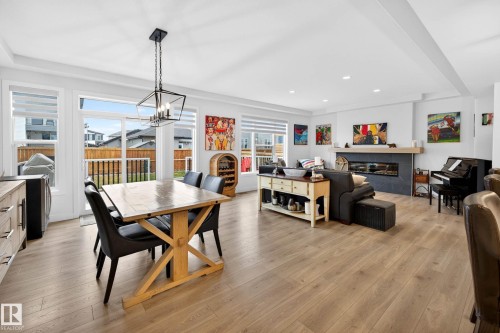 Spacious open concept living area featuring light-toned flooring, a modern fireplace with a dark hearth and light-colored mantle, and large windows with blinds - 345 Meadowview Drive, Fort Saskatchewan, AB - Indoor