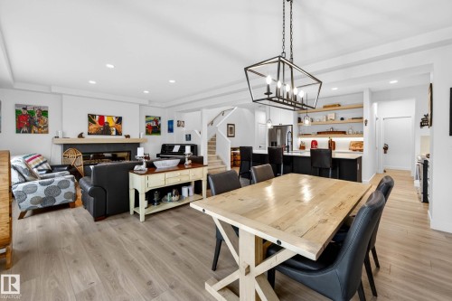 Open-concept living space featuring light-toned flooring, a fireplace with a stone surround, and an island kitchen with dark cabinetry and open shelving - 345 Meadowview Drive, Fort Saskatchewan, AB - Indoor Photo Showing Dining Room