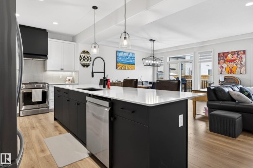The modern kitchen features a large island with a dishwasher, stainless steel appliances, and light-toned flooring - 345 Meadowview Drive, Fort Saskatchewan, AB - Indoor Photo Showing Kitchen