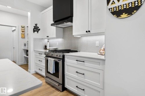 The kitchen features white cabinetry with black hardware, stainless steel appliances, and a black range hood - 345 Meadowview Drive, Fort Saskatchewan, AB - Indoor Photo Showing Kitchen With Upgraded Kitchen