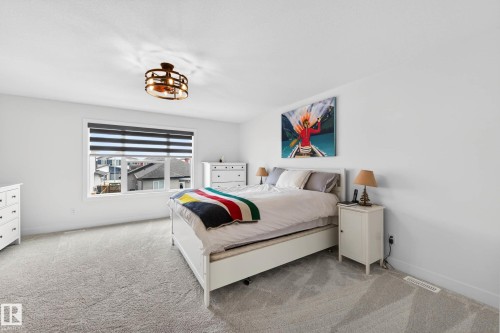 This room features a window with horizontal blinds, a ceiling-mounted light fixture, and light-colored carpet - 345 Meadowview Drive, Fort Saskatchewan, AB - Indoor Photo Showing Bedroom