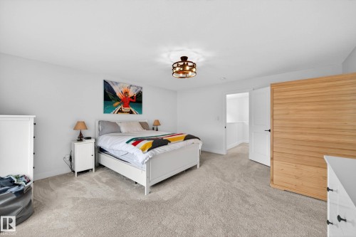 Bedroom featuring light grey carpet, a white framed bed, and a decorative ceiling light fixture - 345 Meadowview Drive, Fort Saskatchewan, AB - Indoor Photo Showing Bedroom