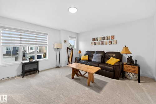 This room features light-colored carpeting, white walls, and a large window with horizontal blinds - 345 Meadowview Drive, Fort Saskatchewan, AB - Indoor Photo Showing Living Room