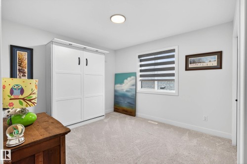 The room features light gray carpeting, a window with horizontal blinds, and a white wall-mounted cabinet - 345 Meadowview Drive, Fort Saskatchewan, AB - Indoor