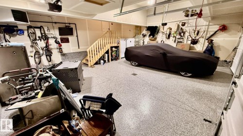 The property features an extensive garage with a speckled epoxy floor coating, painted walls, and a wooden staircase - 345 Meadowview Drive, Fort Saskatchewan, AB - Indoor Photo Showing Gym Room