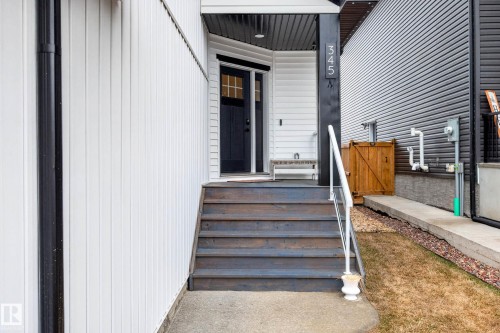 The property features a dark-colored front door with glass panels, complemented by a white exterior facade - 345 Meadowview Drive, Fort Saskatchewan, AB - Outdoor