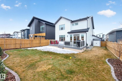 The property features a spacious backyard with a deck, a detached shed with a garage-style door, and wood fencing enclosing the perimeter - 345 Meadowview Drive, Fort Saskatchewan, AB - Outdoor With Deck Patio Veranda