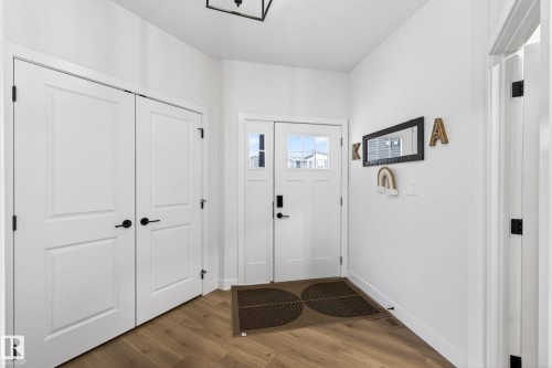 The entryway features light wood flooring, a white front door with upper window panes, and a pair of white doors with black hardware - 345 Meadowview Drive, Fort Saskatchewan, AB - Indoor Photo Showing Other Room