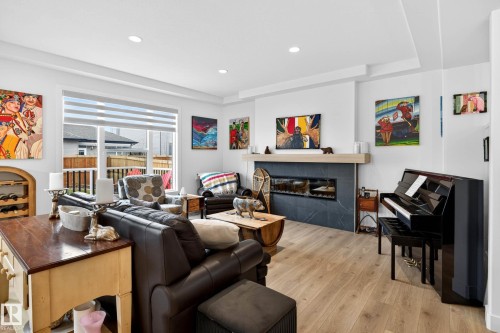 The living room features light-colored flooring, recessed lighting, and a modern fireplace with a dark-toned surround and a light-colored mantel - 345 Meadowview Drive, Fort Saskatchewan, AB - Indoor Photo Showing Other Room With Fireplace