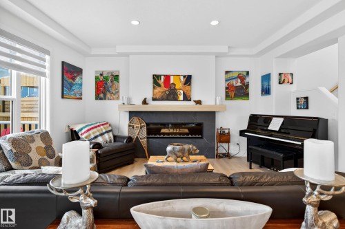 The living area features light-colored flooring, a fireplace with a dark-tiled surround and light mantel, and recessed lighting - 345 Meadowview Drive, Fort Saskatchewan, AB - Indoor Photo Showing Living Room With Fireplace