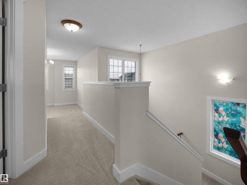 The property offers an inviting upper landing area with neutral-toned walls, carpeted flooring, and white trim - 8361 Shaske Crescent, Edmonton, AB - Indoor Photo Showing Other Room