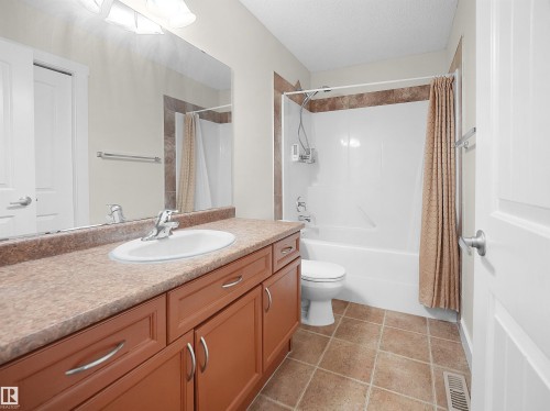 The bathroom features a vanity with a large mirror, a countertop with an integrated sink, and cabinetry with curved handles - 8361 Shaske Crescent, Edmonton, AB - Indoor Photo Showing Bathroom