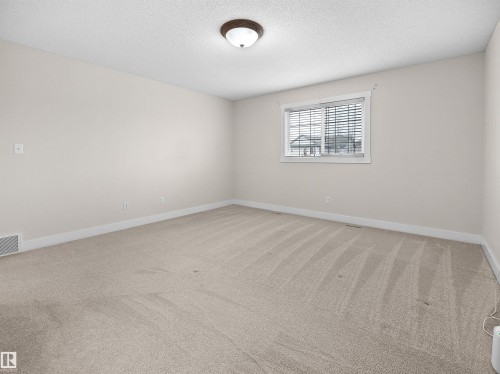 This room features light-colored carpet, a window with blinds, and white walls, creating a bright and airy atmosphere - 8361 Shaske Crescent, Edmonton, AB - Indoor Photo Showing Other Room