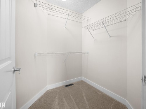 The closet features white wire shelving, neutral carpeting, and white walls - 8361 Shaske Crescent, Edmonton, AB - Indoor With Storage