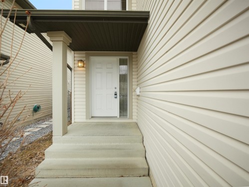 The property features a front entrance with a white panel door and a side window, complemented by an outdoor wall lantern - 8361 Shaske Crescent, Edmonton, AB - Outdoor With Exterior