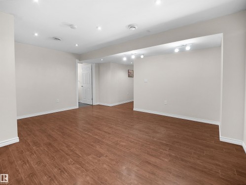 Expansive room featuring wood-look flooring, recessed lighting, and a white paneled door - 8361 Shaske Crescent, Edmonton, AB - Indoor Photo Showing Other Room