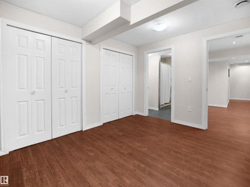 Well-maintained interior space featuring wood-look flooring, light-colored walls, and white bi-fold closet doors - 8361 Shaske Crescent, Edmonton, AB - Indoor Photo Showing Other Room