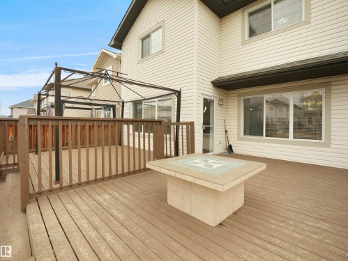 The property features a spacious outdoor deck with wood railings and an outdoor table with a tiled surface - 8361 Shaske Crescent, Edmonton, AB - Outdoor With Deck Patio Veranda With Exterior