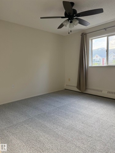 This room features light-colored walls, gray carpet, and a ceiling fan with integrated lighting - 331 10636 120 Street, Edmonton, AB - Indoor Photo Showing Other Room