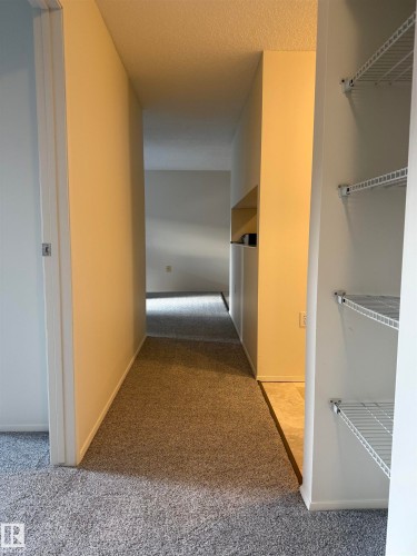 Hallway with carpeted flooring leading to interior spaces - 331 10636 120 Street, Edmonton, AB - Indoor