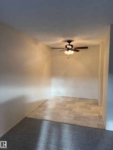This room features a ceiling fan with integrated lighting, a mix of carpet and tiled flooring, and light-colored walls - 331 10636 120 Street, Edmonton, AB - Indoor Photo Showing Other Room