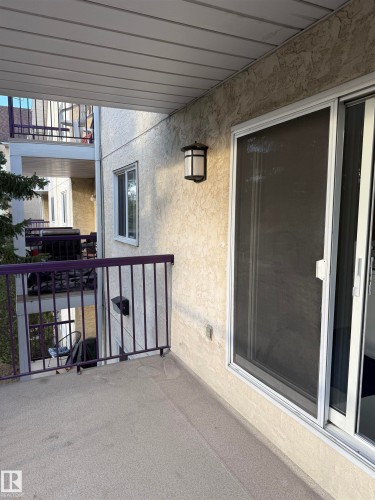 This property features a private balcony with a textured concrete floor and purple metal railings - 331 10636 120 Street, Edmonton, AB - Outdoor With Balcony With Exterior
