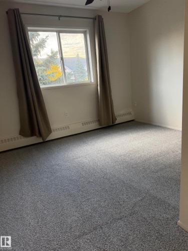 The room features a window providing natural light, grey carpeting, and white walls - 331 10636 120 Street, Edmonton, AB - Indoor Photo Showing Other Room