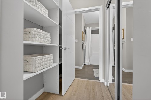 This area features a closet with built-in shelving and a sliding mirrored door - 127 1154 Adamson Drive, Edmonton, AB - Indoor Photo Showing Other Room