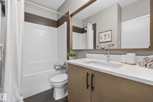 Bathroom featuring a vanity with a white countertop and a rectangular sink, a large mirror, and a shower-tub combination - 127 1154 Adamson Drive, Edmonton, AB - Indoor Photo Showing Bathroom