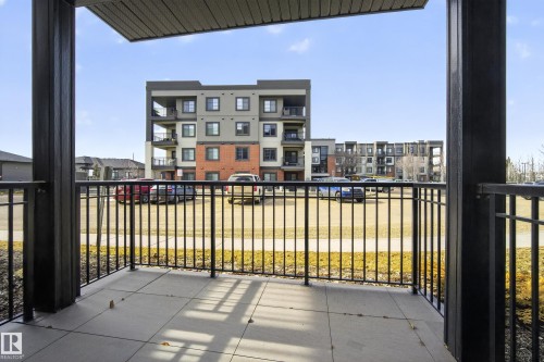 This property features a private balcony with a tiled floor and black metal railings, offering views of nearby buildings and open green space - 127 1154 Adamson Drive, Edmonton, AB - Outdoor With Balcony