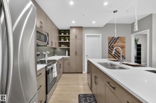 This kitchen features stainless steel appliances, including a refrigerator, microwave, and oven - 127 1154 Adamson Drive, Edmonton, AB - Indoor Photo Showing Kitchen With Stainless Steel Kitchen With Double Sink With Upgraded Kitchen