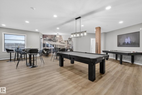 Recreational room featuring two billiard tables, light wood-style flooring, and a decorative brick column - 127 1154 Adamson Drive, Edmonton, AB - Indoor Photo Showing Other Room