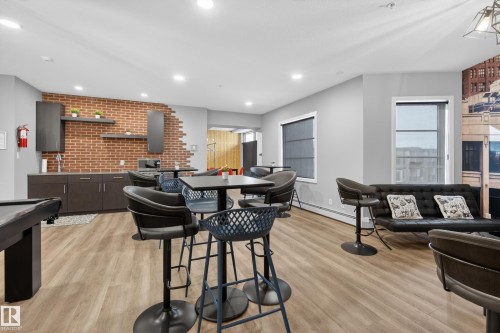 Well-lit common area featuring light-toned flooring, a brick accent wall, and recessed lighting - 127 1154 Adamson Drive, Edmonton, AB - Indoor