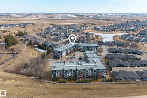Aerial view of the property and its surrounding environment, featuring a modern apartment building with a flat roof and a parking lot - 127 1154 Adamson Drive, Edmonton, AB - Outdoor With View