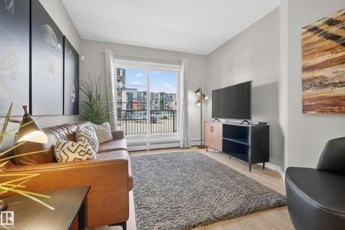 Living area featuring light-toned flooring, a sliding glass door providing access to an exterior balcony, and light gray walls - 127 1154 Adamson Drive, Edmonton, AB - Indoor