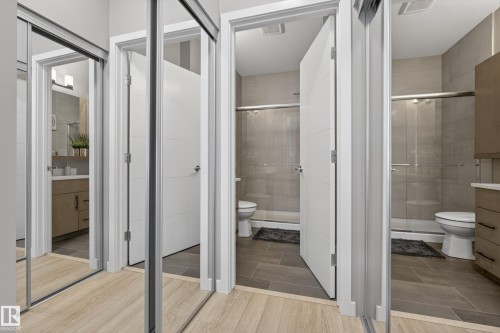 This contemporary bathroom features light wood-look flooring, a modern white door, and a sleek vanity with a rectangular basin - 127 1154 Adamson Drive, Edmonton, AB - Indoor Photo Showing Bathroom