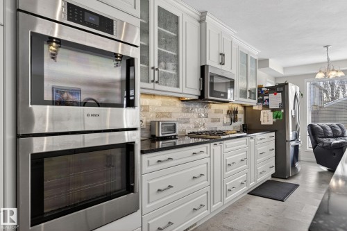 The kitchen features white cabinetry with dark handles, stainless steel appliances, and dark countertops - 19 Escada Close, St. Albert, AB - Indoor Photo Showing Kitchen With Upgraded Kitchen