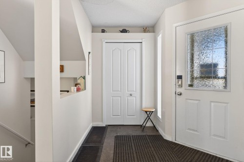 The entryway features a white door with a textured glass insert, a white folding door, and dark patterned floor mats - 19 Escada Close, St. Albert, AB - Indoor Photo Showing Other Room