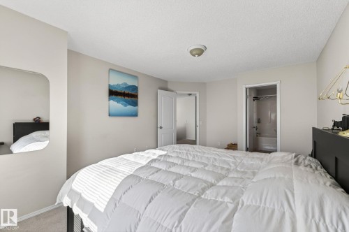 This room features light-colored walls, a ceiling light fixture, and an entry to a bathroom with a white tub and shower - 19 Escada Close, St. Albert, AB - Indoor Photo Showing Bedroom