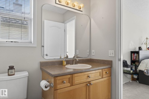 Bathroom vanity featuring a light wood cabinet with silver hardware, an integrated sink, and a large mirror with overhead lighting - 19 Escada Close, St. Albert, AB - Indoor Photo Showing Bathroom