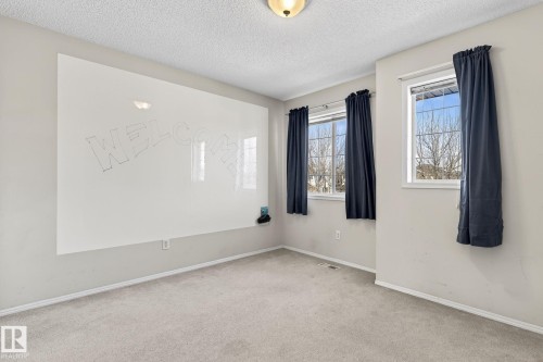 This room features light-colored carpeting, two windows with dark curtains, and a large white board on one wall - 19 Escada Close, St. Albert, AB - Indoor Photo Showing Other Room