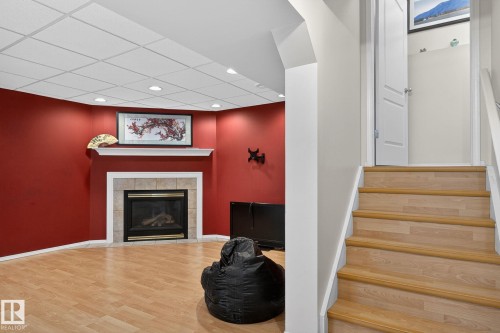 This room features a corner fireplace with a tiled surround and mantel, light-colored flooring, and recessed lighting - 19 Escada Close, St. Albert, AB - Indoor With Fireplace